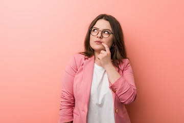 Wall Mural - Young plus size business caucasian woman looking sideways with doubtful and skeptical expression.