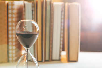 Wall Mural - hourglass with books on wooden table