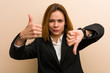 © Asier - Young caucasian business woman showing thumbs up and thumbs down, difficult choose concept