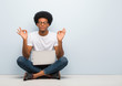 © Asier - Young black man sitting on the floor with a laptop performing yoga