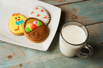Easter homemade shortbreads on a porcelain plate, on wooden background with Cup of milk.