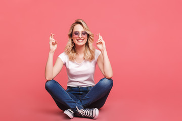 Poster - Portrait of smiling blond woman 20s wearing vintage sunglasses laughing while sitting on floor with legs crossed