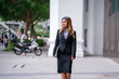 Portrait of a young, beautiful, tanned Southeast Asian business woman in a suit smiling confidently as she stands in the city during the day. She is looking forward to her future as a professional.