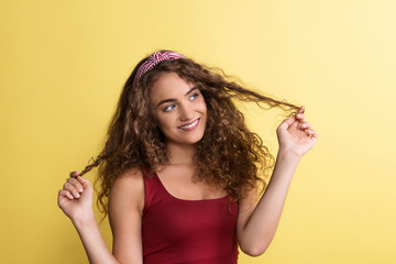 Wall Mural - Portrait of a young woman with headband in a studio on a yellow background.