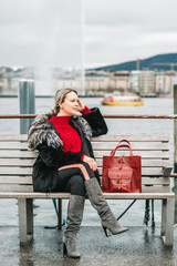 Wall Mural - outdoor fashion portrait of beautiful woman with blond hair, wearing black fur coat, red pullover, s