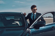 © gstockstudio - Luxury style. Handsome young businessman entering his car while standing outdoors