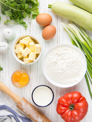 Wall Mural - Ingredients for cooking quiche with vegetables (squash, tomatoes, cheese, herbs, green onions), open tart, French cuisine, traditional pastries