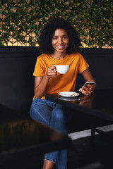 Canvas Print - Portrait of a young woman sitting in cafe with smartphone