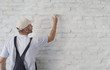 © triocean - Painting a white brick wall with a paint brush