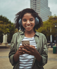 Wall Mural - Young woman listening to music using smart phone through headphone