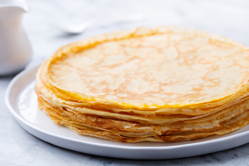 Wall Mural - Crepes, thin pancakes with honey on a white plate. Close up.
