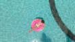 © Denis - Young female freelancer sitting with a tablet in an inflatable circle in the pool. Aerial view