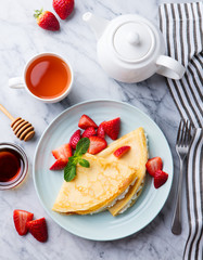 Wall Mural - Crepes, thin pancakes with fresh strawberry and ricotta, cream cheese. Marble background. Top view.