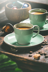 Cups of coffee and capsules, close up