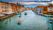 Vaporetto and commercial boats traverse the Grand Canal in Venice, Italy, faces and logos blurred for commercial use