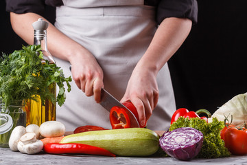 young woman slicing peppers in a gray apron