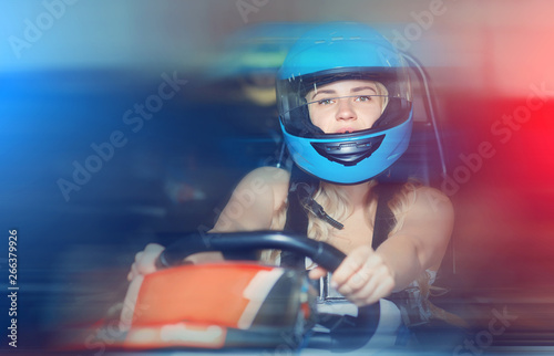 Fototapety Karting  kobieta-w-kasku-jazdy-samochodem-na-karting-z-innymi-ludzmi