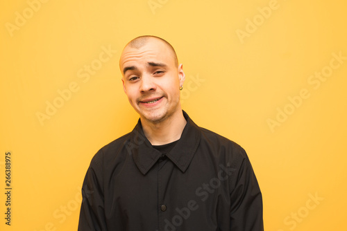 Sheerful Guy In Black Jacket Makes A Funny Face A Close Up Portrait On A Yellow Background Wearing Grillz Teeth Portrait Of A Rapper In A Stylish Clothes On A Yellow Background