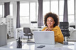 © nenadaksic - Beautiful smiling mixed race businesswoman dressed casual sitting in office and using laptop.