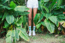 Legs Of A Young Woman Standing Near The Trees