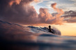 © Olga Sinenko/Stocksy - Silhouette of woman surfing in the ocean at sunset. Beautiful clouds. Vivid warm colors.