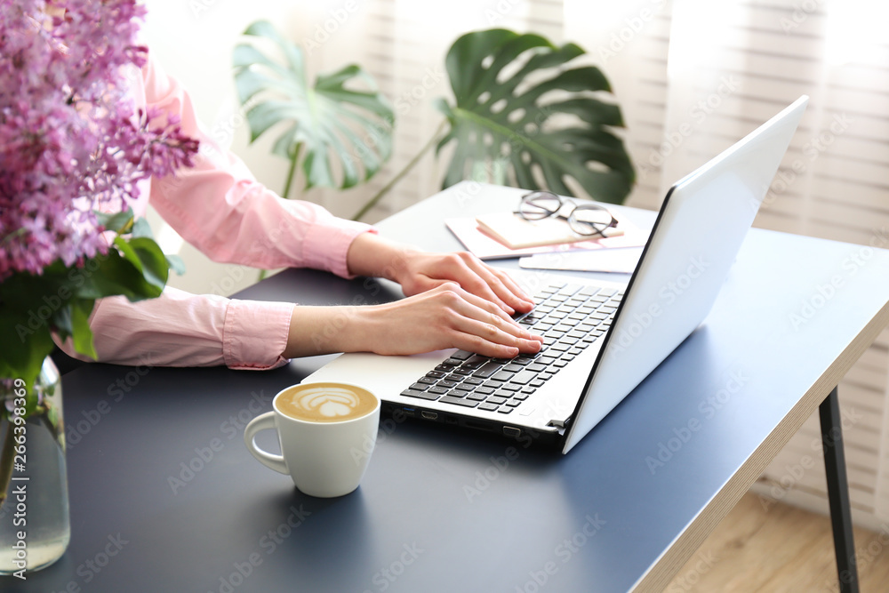Feminine freelance workspace concept. Woman's hands typing on white laptopp with black keyboard, desk with matte blue table top. Freelance blogger writing an article. Close up, copy space for text. - obrazy, fototapety, plakaty 