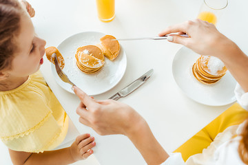 Wall Mural - overhead view of mother feeding daughter with pancakes