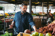 © Rob and Julia Campbell/Stocksy - 40's man choosing fruits and vegetables at the local grocery sto