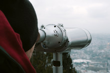 Young Man Looks Through Binoculars On A City