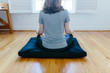 © Jakob Lagerstedt/Stocksy - Woman sitting on a meditation cushion facing a window