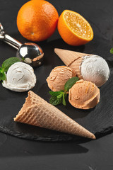 Wall Mural - Close-up shot of a creamy and orange ice cream served on a dark slate, black background.