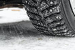 Deep tread of winter studded tires for snowy road. Wheel close-up on a slippery snowy winter road.