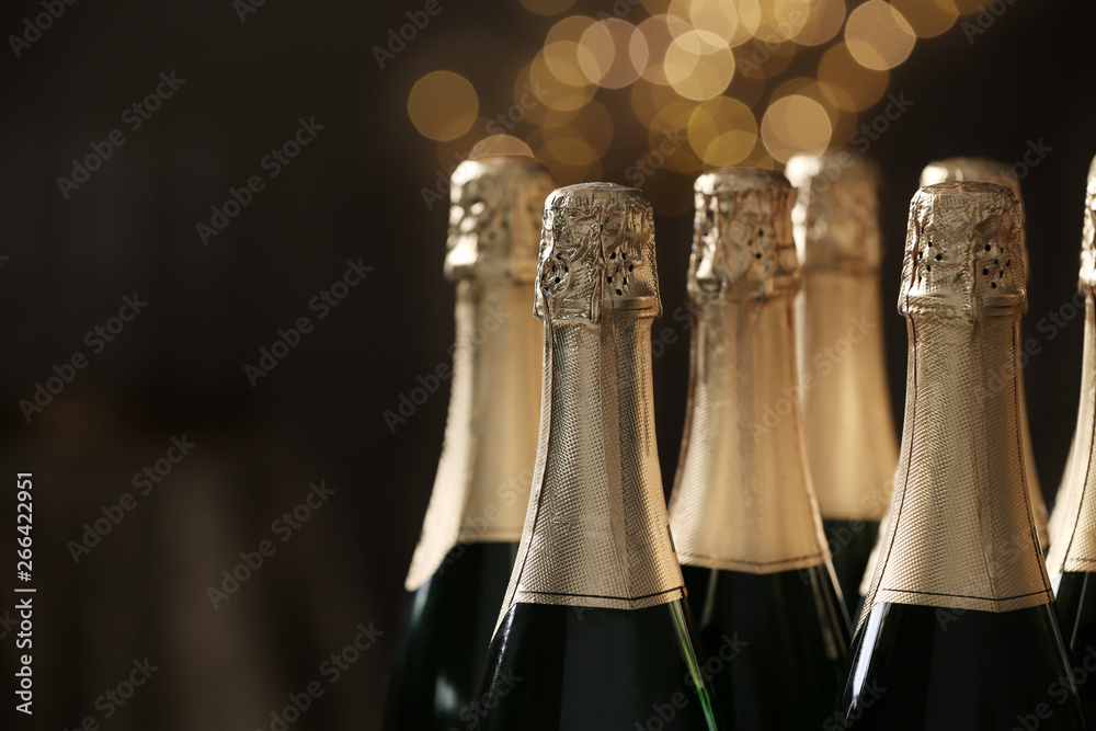 Many bottles of champagne on blurred background, closeup. Space for text - obrazy, fototapety, plakaty 