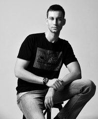 Young handsome man in casual wear is sitting on a step ladder