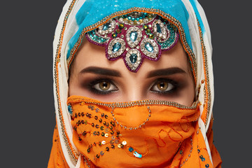 Wall Mural - Studio shot of a chrming female wearing the colorful hijab decorated with sequins and jewelry. Arabic style.