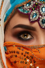 Wall Mural - Studio shot of a chrming female wearing the colorful hijab decorated with sequins and jewelry. Arabic style.