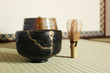 Kintsugi a repair of crack pottery black tea cup  at tatami mat Japanese tea room blur background