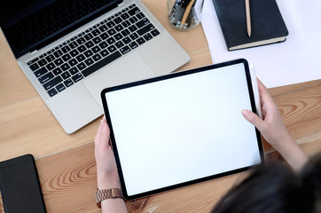 Shot of female hand holding tablet with blank screen while sitting at office desk.