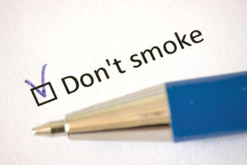 Questionnaire –  blue pen and the inscription DON'T SMOKE with check mark on the white paper