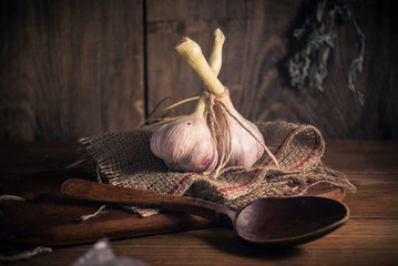 Two heads of garlic on rural background with sackcloth and wood