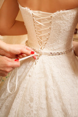 Wedding day. Morning of the bride. Fees. Dressing. Hands tighten the wedding dress. Close up