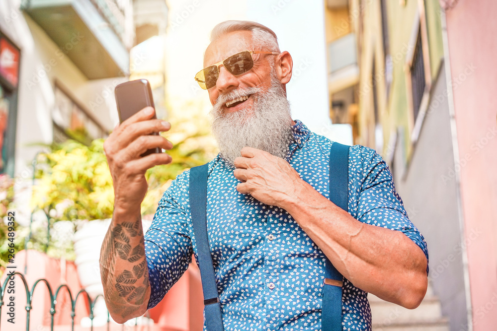 Trendy senior man using smartphone app in downtown center outdoor - Mature fashion male having fun with new trends technology - Tech and joyful elderly lifestyle concept - Focus on his face - obrazy, fototapety, plakaty 