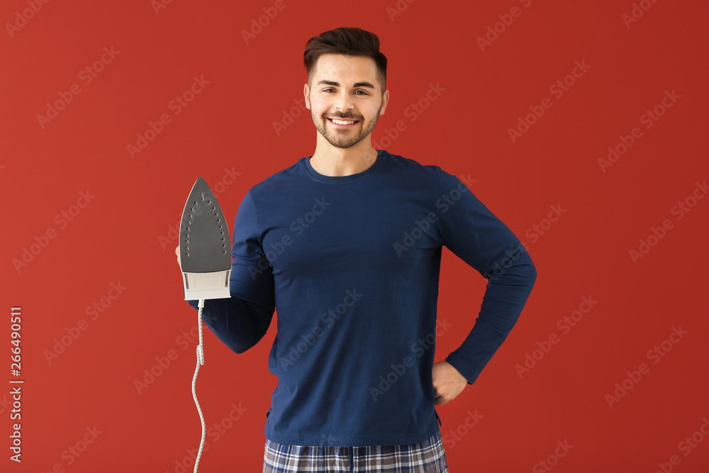 Young man with iron on color background