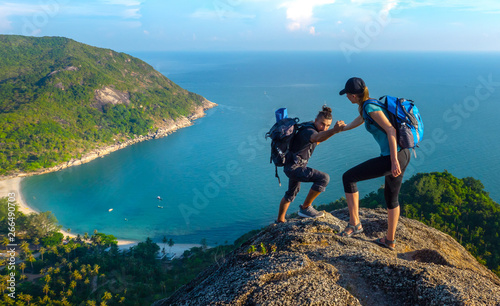Fotografía Man and woman hiking on the top of cliff in summer mountains at morning time and