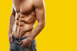 © Dragosh - Close up of naked torso of strong man in jeans posing in studio yellow screen chrome key background. Copy space.