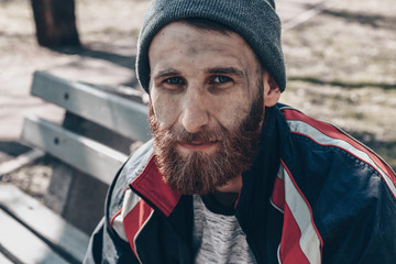 Poor homeless man sitting on bench outdoors