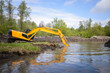 Big excavator puts its shovel under the water to dig make river canal more deep and clean it of different garbage
