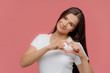 © VK Studio - Smiling pleased brunette female model shapes heart sign, expresses love to boyfriend, dressed in casual white t shirt, isolated over pink background. You are my valentine! Body language concept