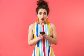 Canvas Print - Shocked pretty redhead woman in dress holding smartphone