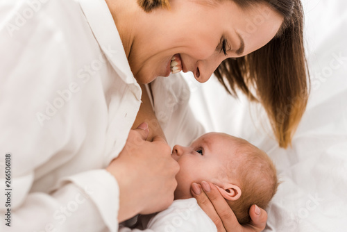 Fotomural Smiling young mother in white t-shirt breastfeeding baby